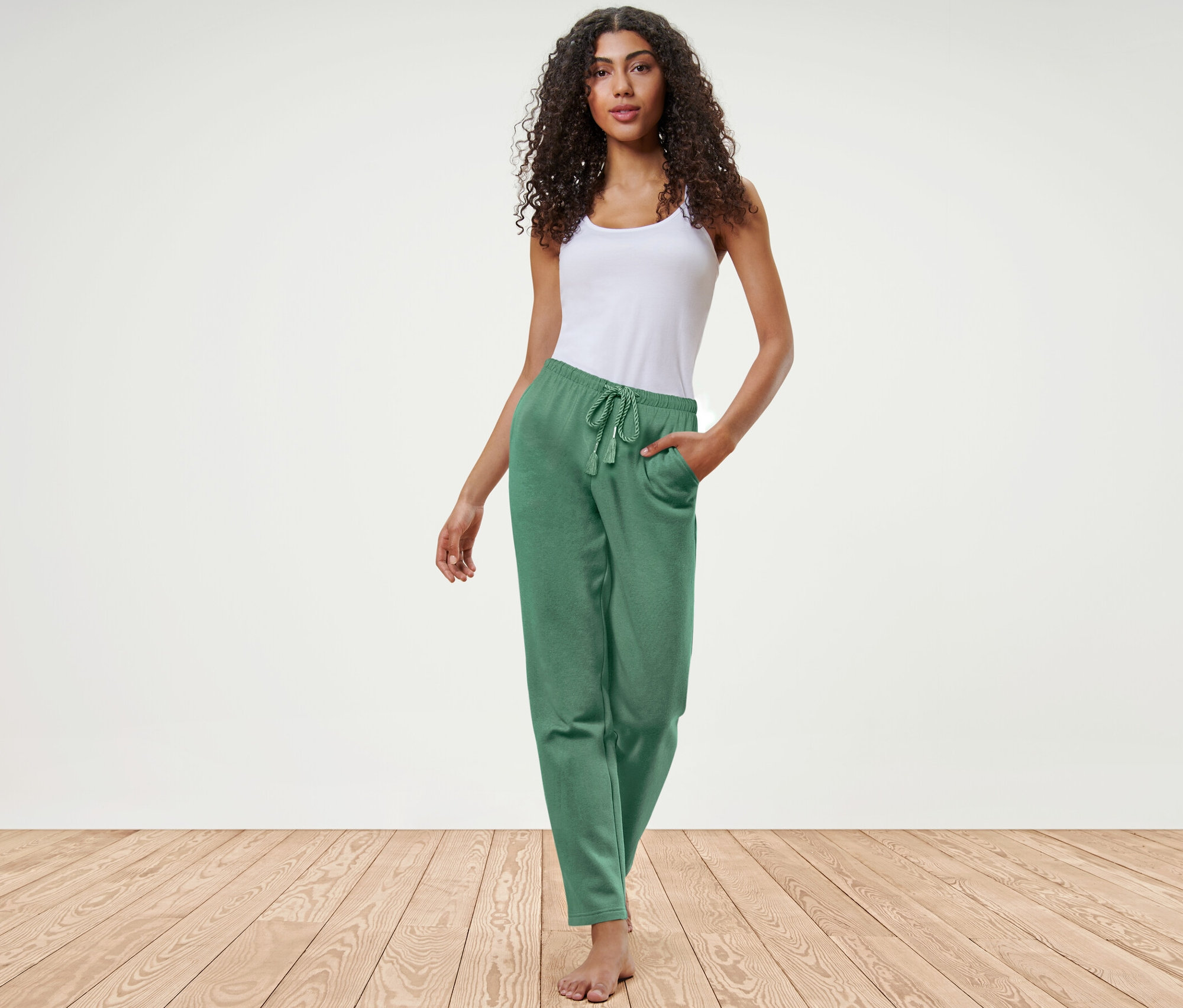 Kobieta pozuje w zielonych spodniach rekreacyjnych i białym topie.