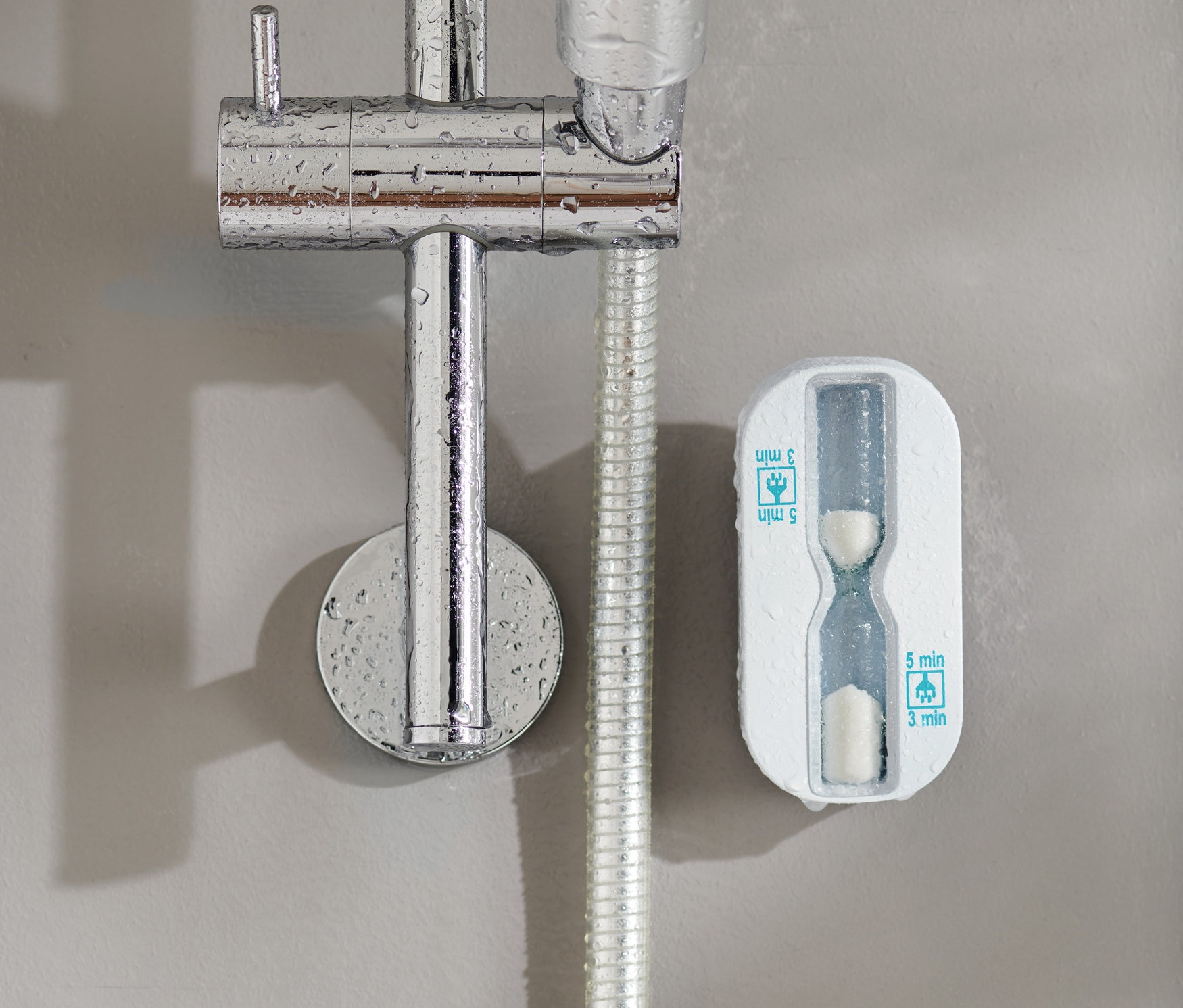 Klepsydra prysznicowa przymocowana do ściany obok głowicy prysznicowej.