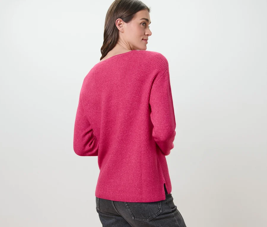 Kobieta ma na sobie malinowy sweter o grubym splocie.