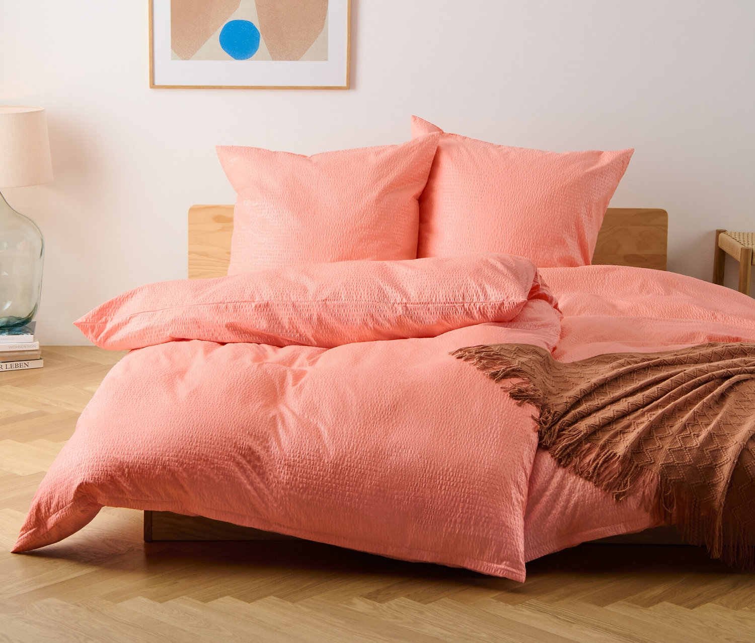 Widok z przodu na łóżko z pościelą z kory w standardowym i niestandardowym rozmiarze w kolorze brzoskwiniowym.