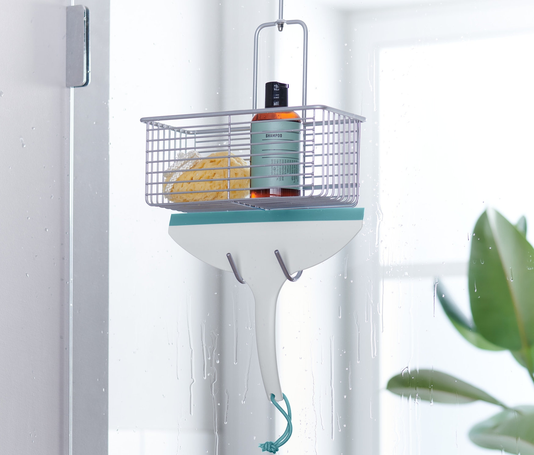 Ściągaczka do wody wisi na drzwiach prysznicowych.