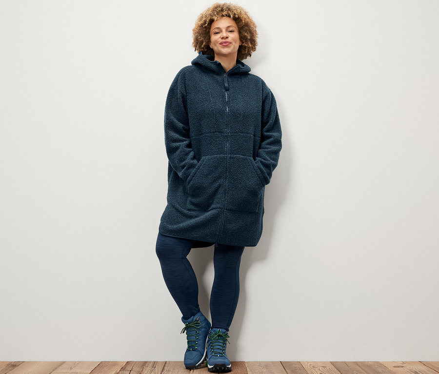 Kobieta pozuje w legginsach sportowych i pluszowym płaszczu oversize.