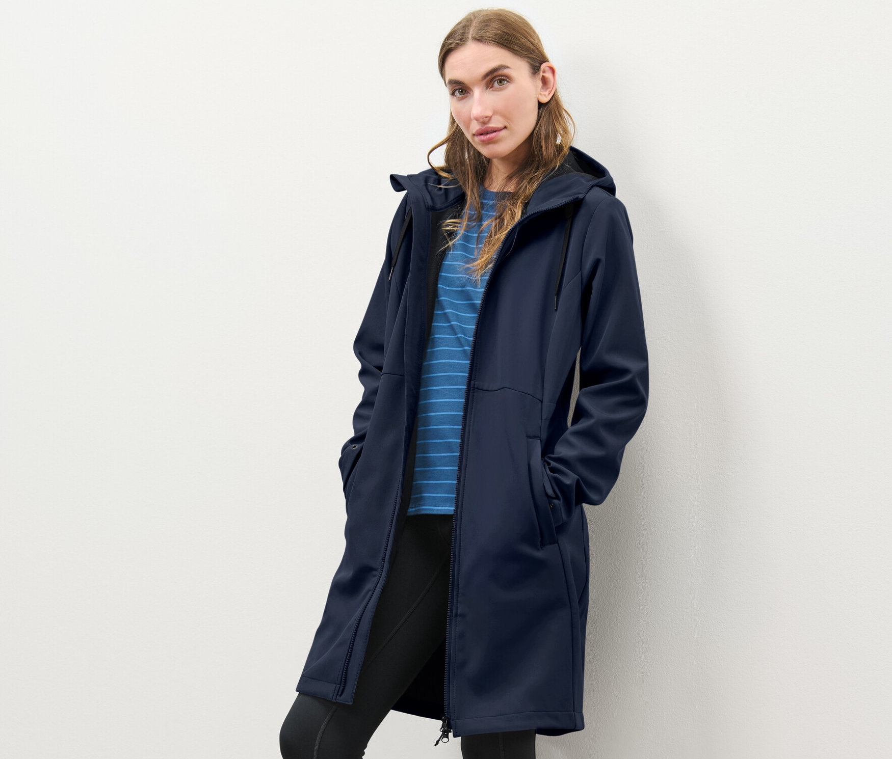 Kobieta pozuje w niebieskim płaszczu softshellowym.