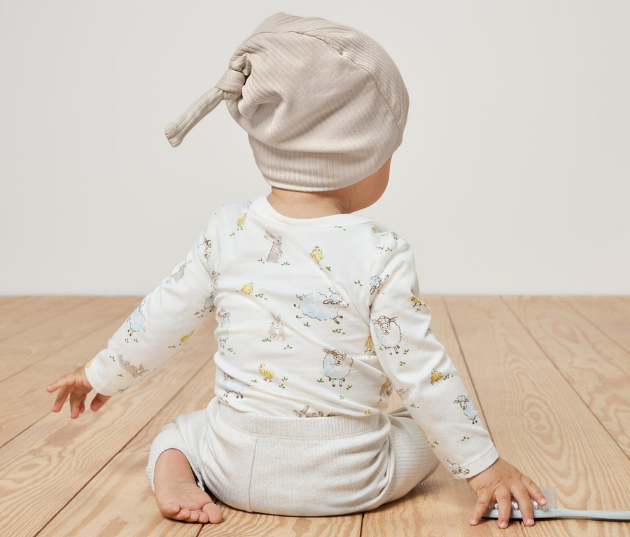 Dziecko siedzi tyłem do kamery i ma na sobie czapki z dżerseju, 2 sztuki.