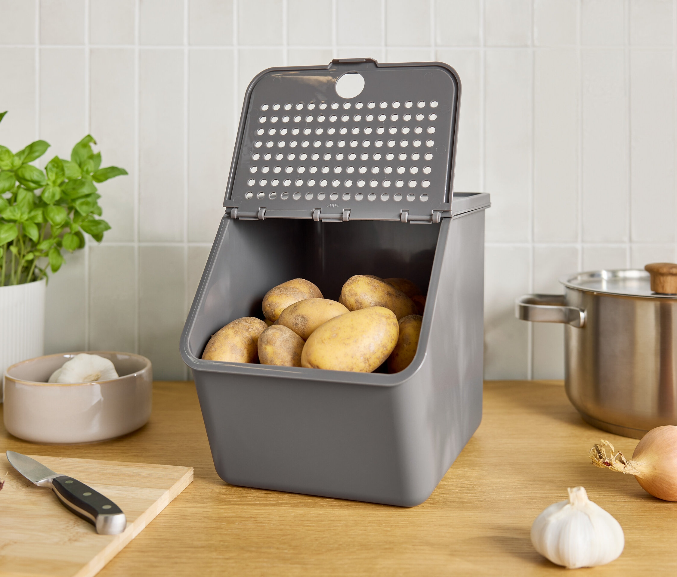 Szary pojemnik z ziemniakami na blacie kuchennym.