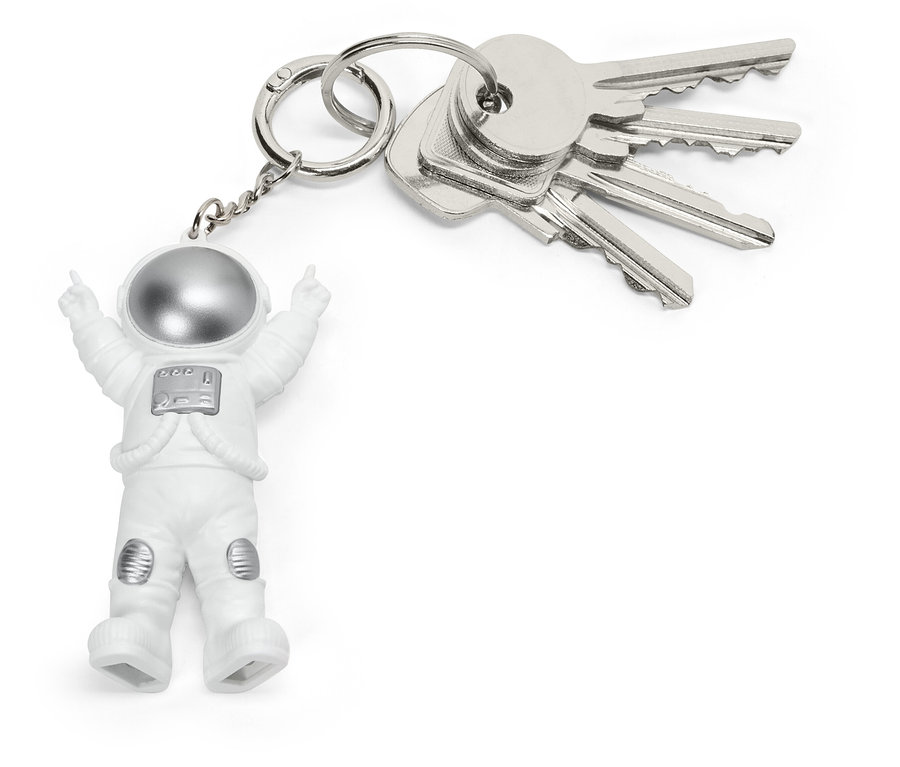 Brelok z małą figurką astronauty w białym kombinezonie i srebrnym hełmie, przymocowany do pęku srebrnych kluczy.