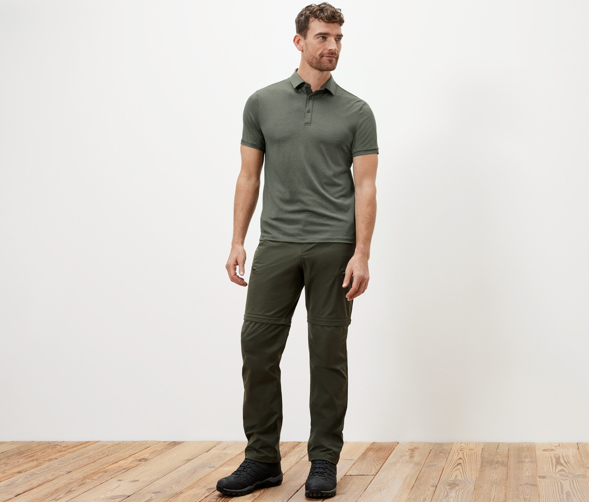 Mężczyzna stoi w funkcyjnej koszulce polo khaki.