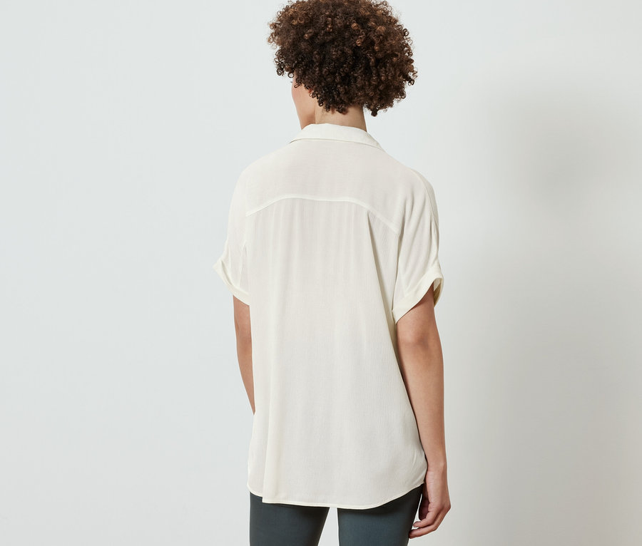 Tył kobiety w kremowej bluzce.