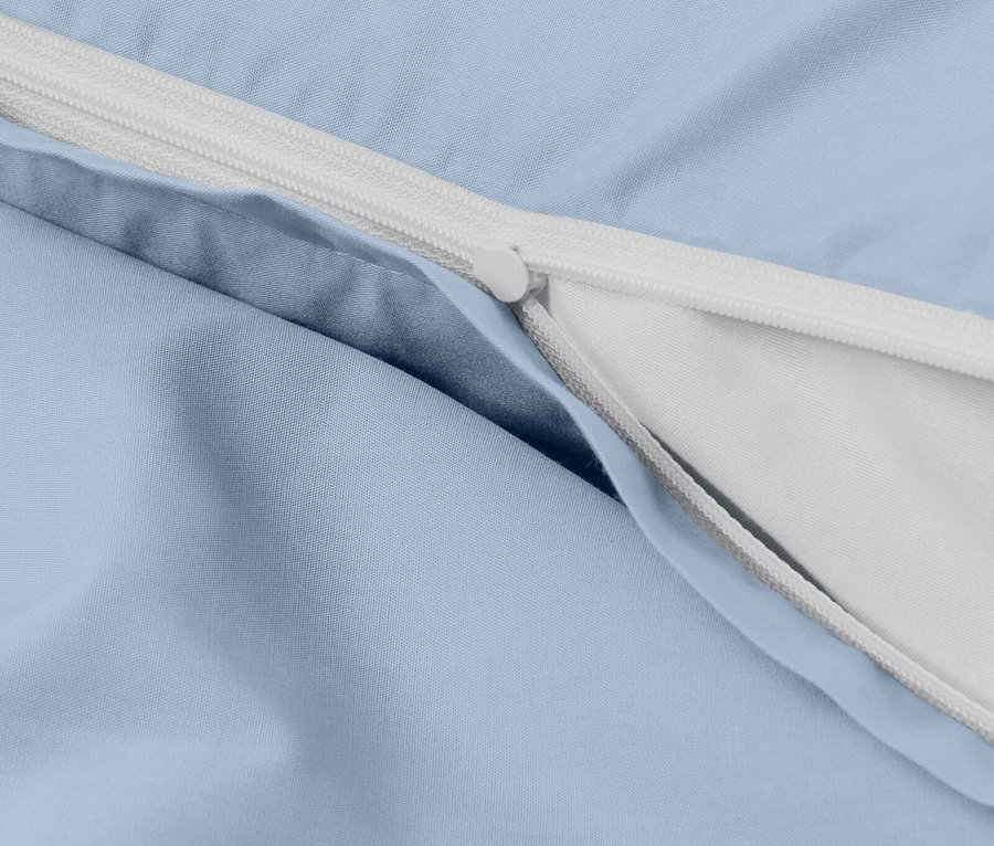 Szczegół jasnoniebieskiej poszewki na kołdrę z białym zamkiem błyskawicznym.