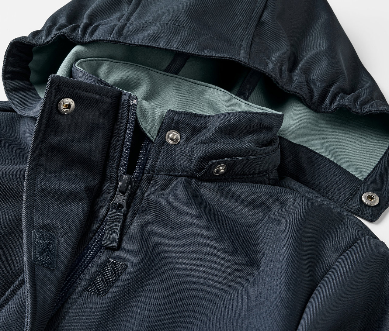 Zbliżenie na płaszcz z softshellu dla dzieci z kapturem i zamkiem błyskawicznym.