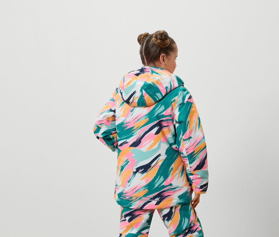 Z tyłu widać dziewczynę w kolorowej kurtce i spodniach.