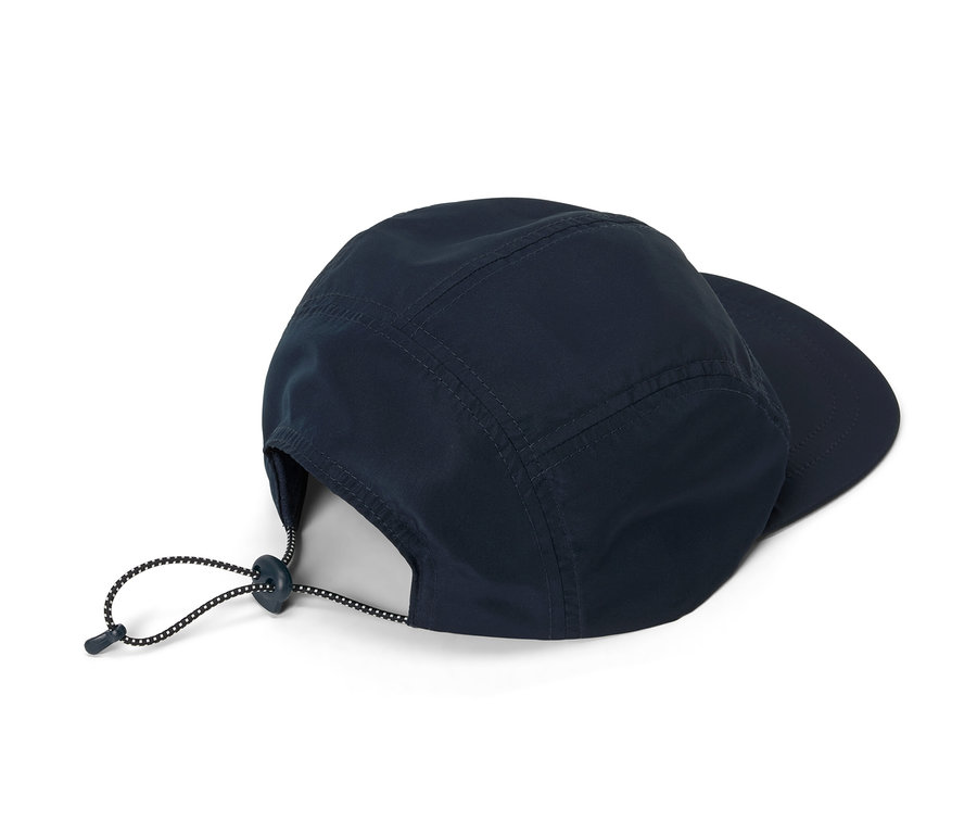 Granatowa czapka z daszkiem leży na białym tle.