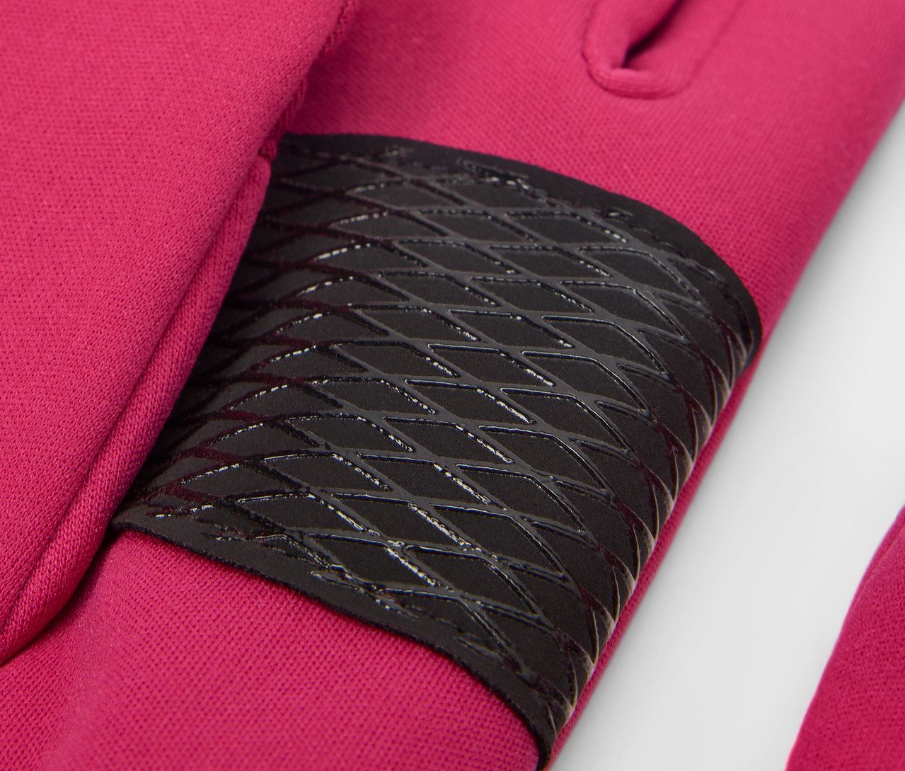 Zbliżenie na malinowe rękawiczki z softshellu dla dzieci z czarnym elementem antypoślizgowym.