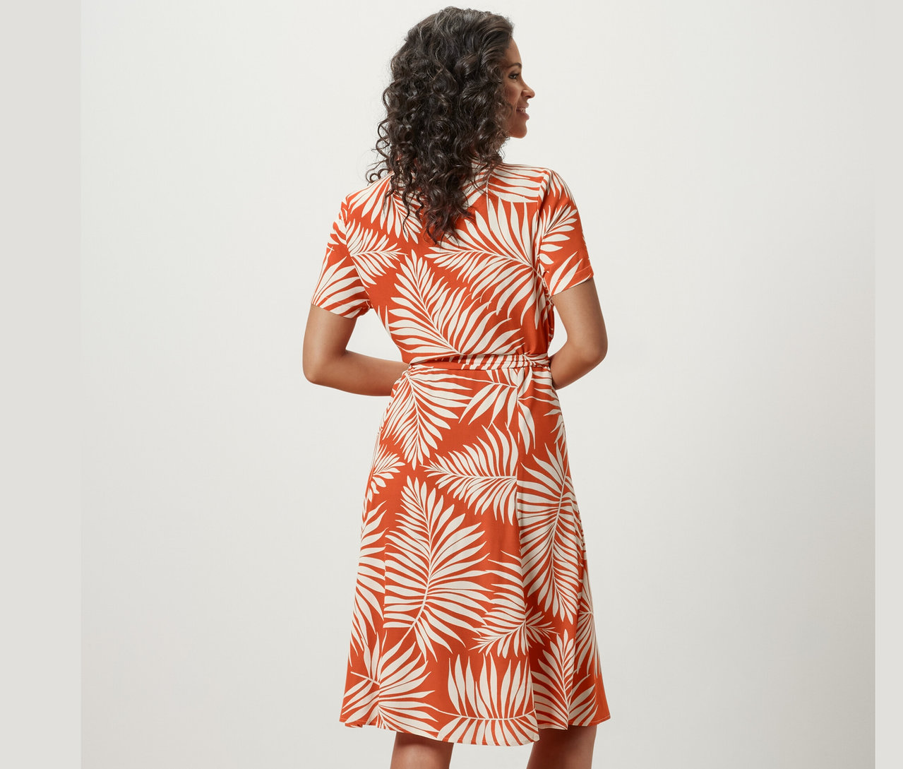 Kobieta pozuje w wzorzystej sukience koszulowej.