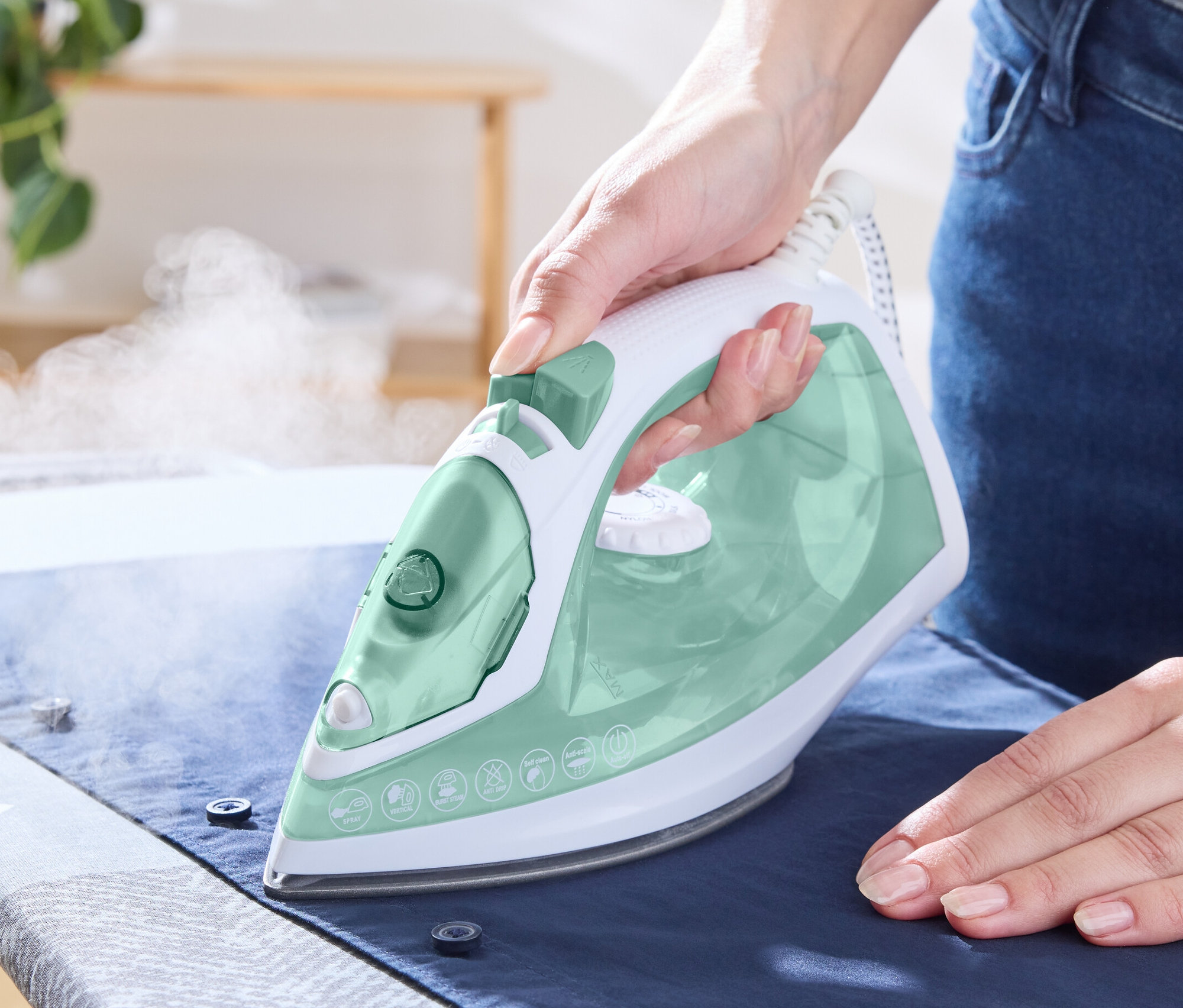 Kobieta prasuje koszulę żelazkiem parowym.