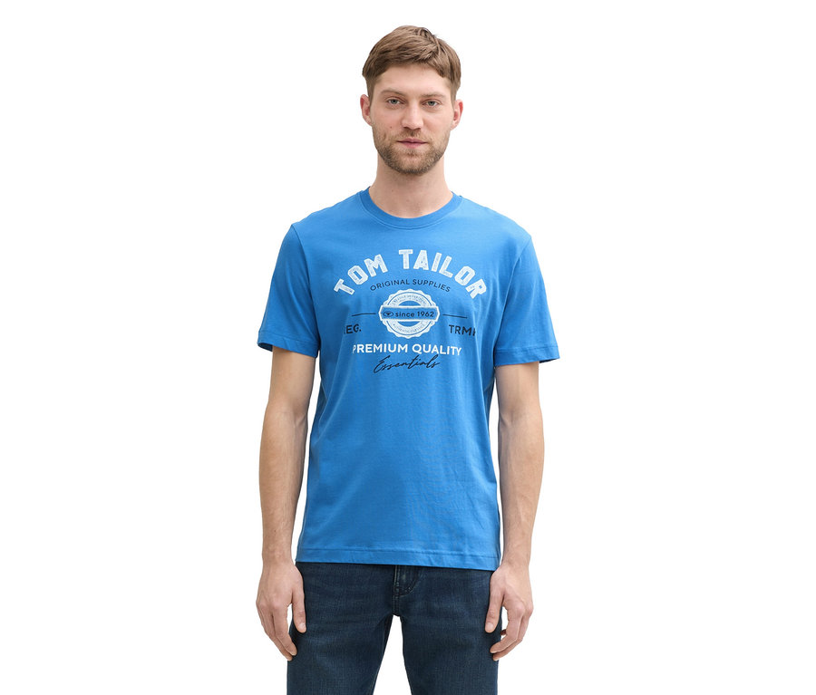 Mężczyzna ma na sobie koszulkę z logo Tom Tailor w kolorze sapphire blue i dżinsy.