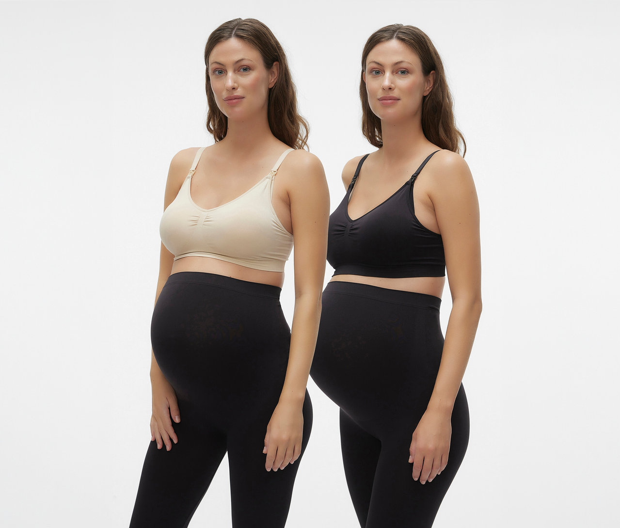 Dwie kobiety w ciąży ubrane w MAMALICIOUS MLILJA FEED ME BRA 2-P NOOS i czarne legginsy na białym tle.