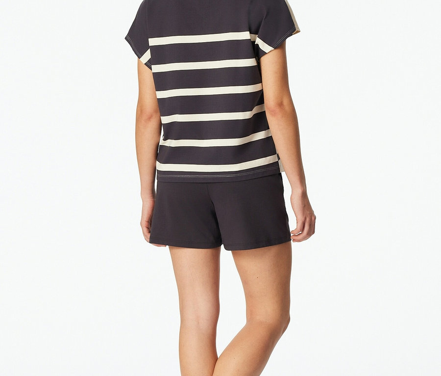 Kobieta od tyłu w szaro-białej koszulce w paski i szortach.