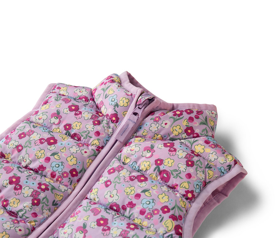 Zbliżenie na liliową, pikowaną kamizelkę we wzory kwiatowe z zamkiem błyskawicznym.