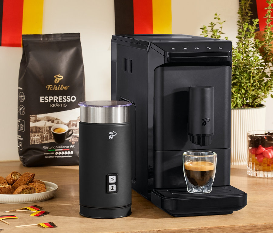 Na stole stoi automatyczny ekspres do kawy »Esperto mini« Black, elektryczny spieniacz do mleka (czarny) i 2 szklanki o podwójnych ściankach do espresso.