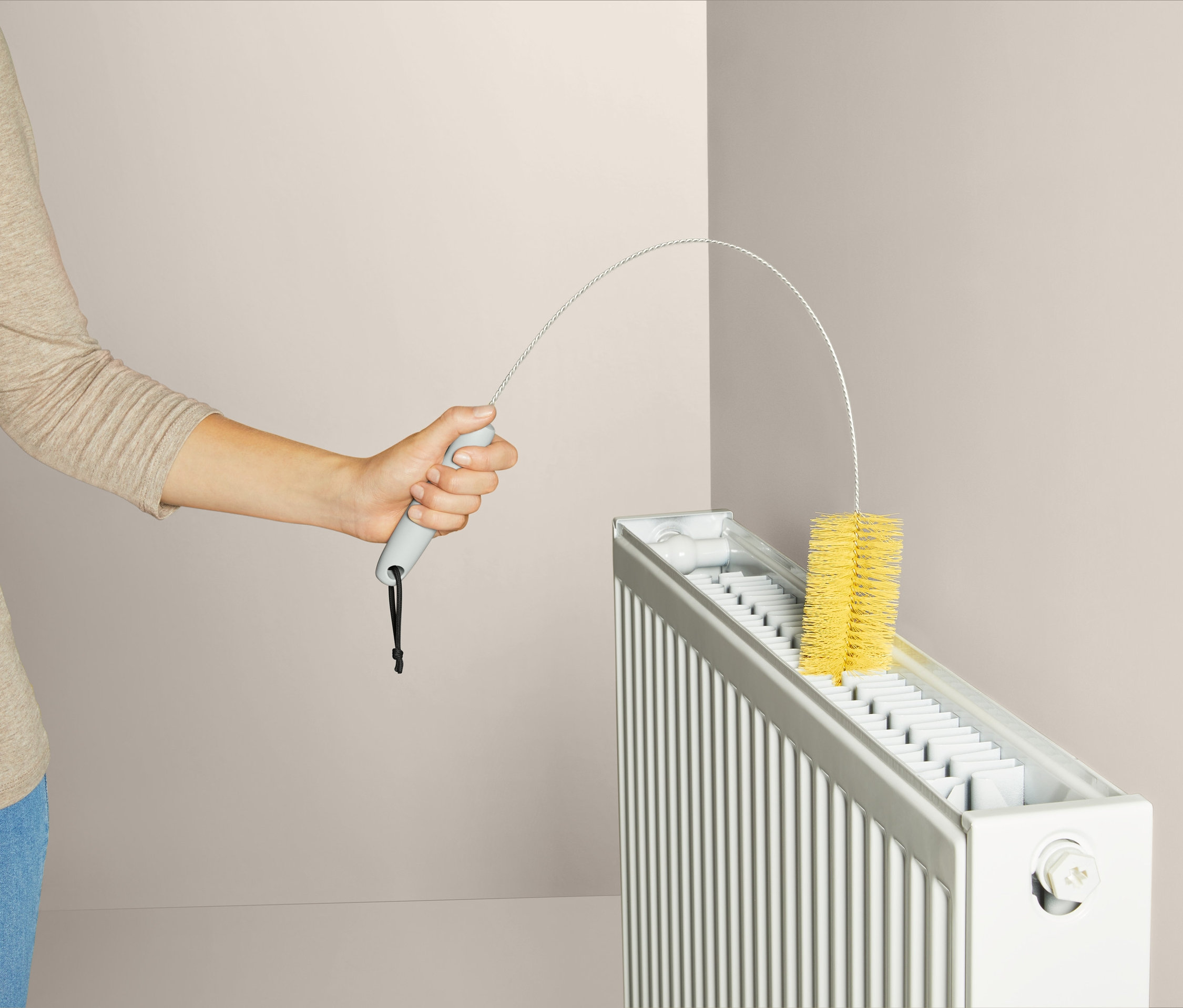 Kobieta czyści kaloryfer szczotką do kaloryfera.