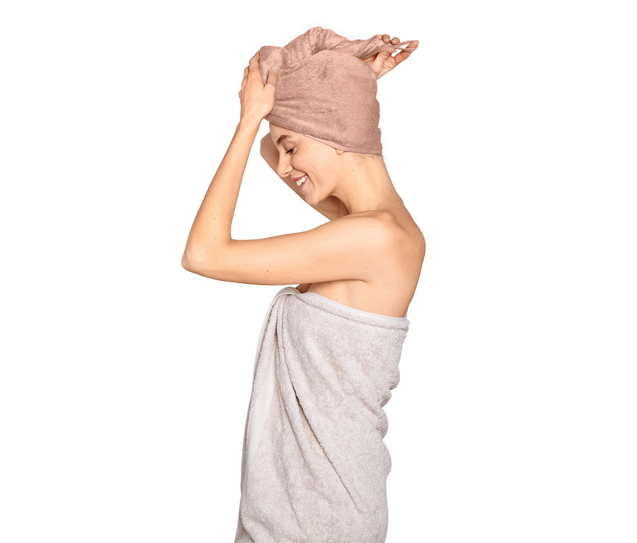 Kobieta poprawia różowy ręcznik turban na głowie.