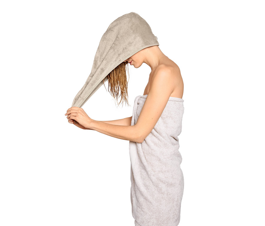 Kobieta zakłada na mokre włosy beżowy ręcznik turban.