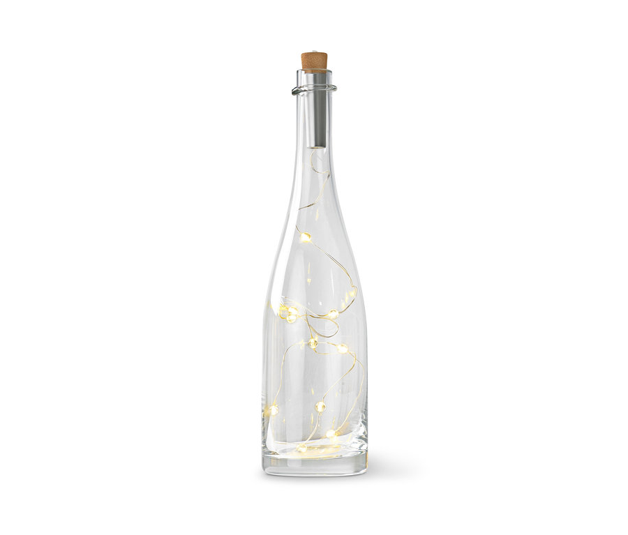 Przezroczysta szklana butelka z korkiem i łańcuchem świetlnym w środku.