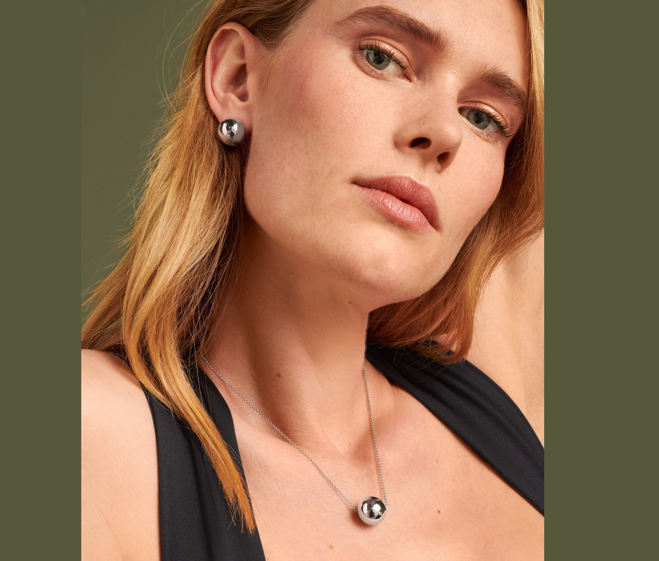 Blondynka nosi kolczyki na sztyfcie Globe i naszyjnik Globe.