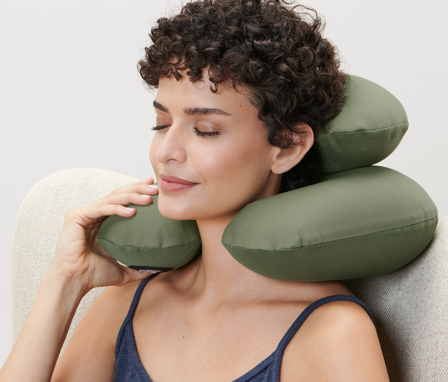 Kobieta siedzi w fotelu i używa nadmuchiwanej poduszki pod kark.