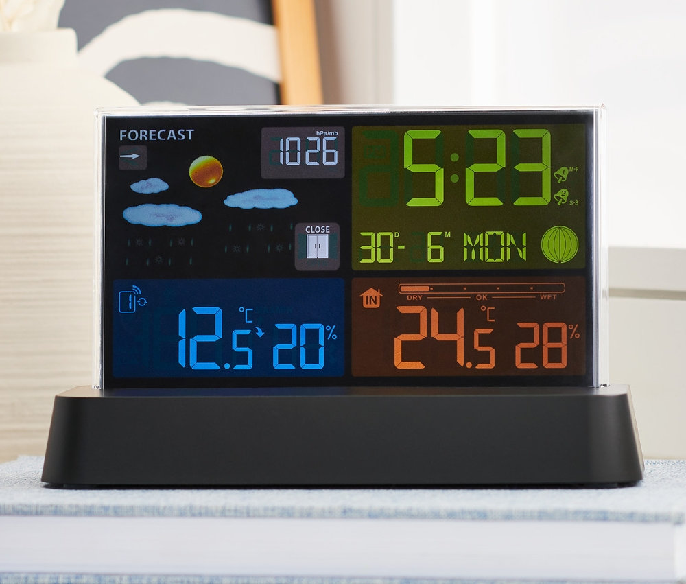 Radiowa stacja pogodowa z kolorowym wyświetlaczem LC stoi na książce.