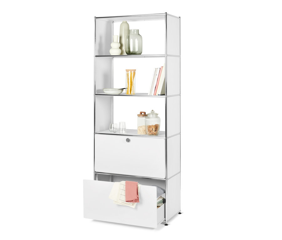 Biały regał metalowy »CN3« z 2 szufladami. Na półkach wazony, szklanki, książki i jedzenie.