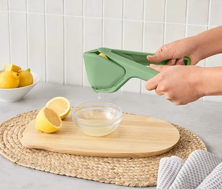 Kobieta wyciska cytrynę do miski za pomocą ergonomicznej wyciskarki do cytrusów.