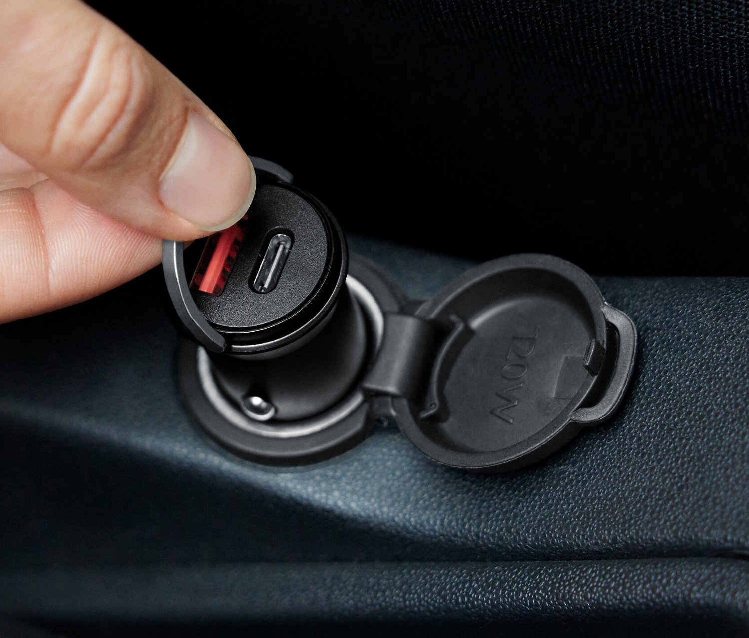 Ręka wkłada szybką ładowarkę samochodową do gniazda.