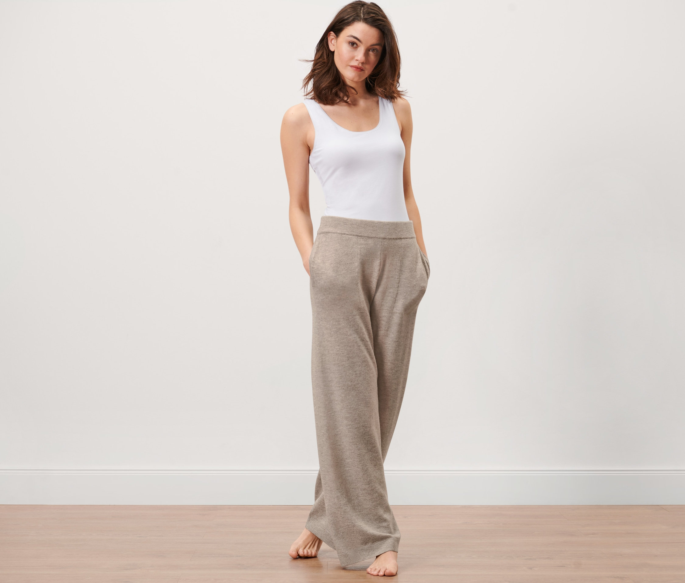 Kobieta stoi z rękami w kieszeniach spodni rekreacyjnych z dzianiny.