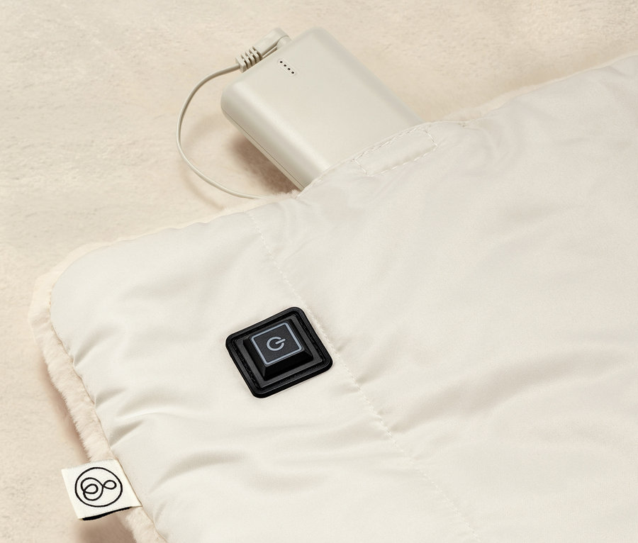 Szczegółowy widok akumulatorowego poncho elektrycznego z przyciskiem sterującym i podłączonym akumulatorem.