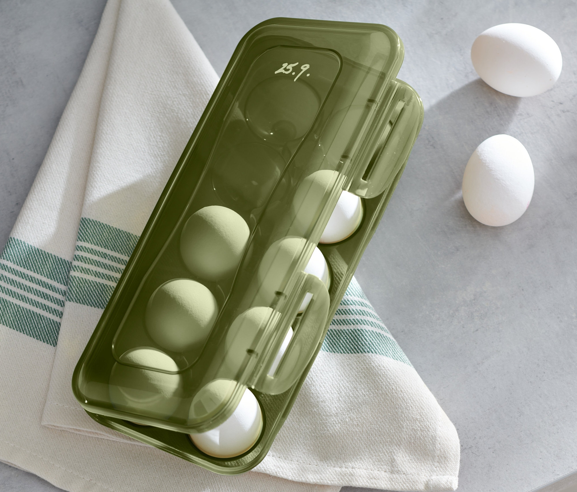 Zielone pudełko na jajka z jajkami na lnianej ściereczce.