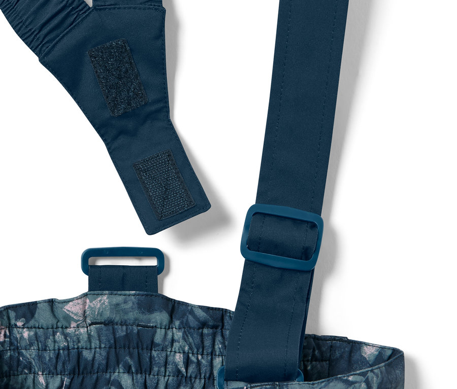 Szczegółowy widok dziecięcych spodni narciarskich z nadrukiem na całej powierzchni, w tym regulowanych ramiączek i klamer.