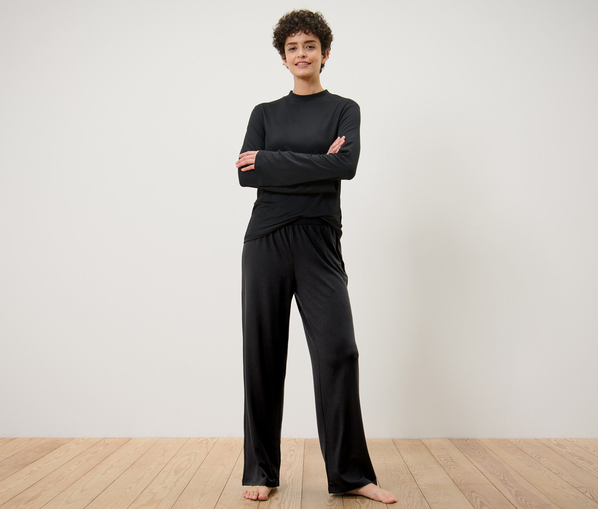 Kobieta stoi ze skrzyżowanymi ramionami, ubrana w szerokie spodnie sportowe.