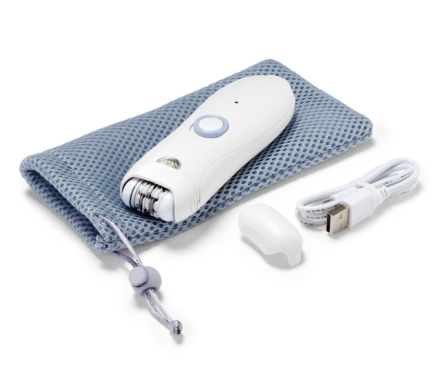 Biały depilator do twarzy leży na niebieskim woreczku ze sznurkiem obok kabla ładującego i nasadki.