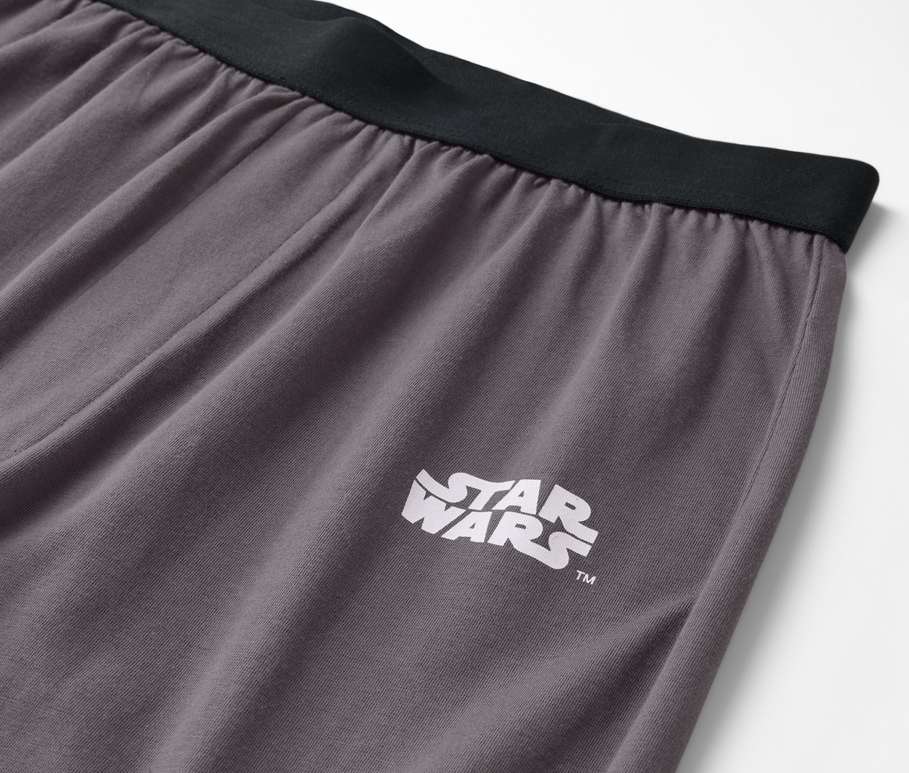 Szczegół szarych spodni z czarnym pasem i logo Star Wars.