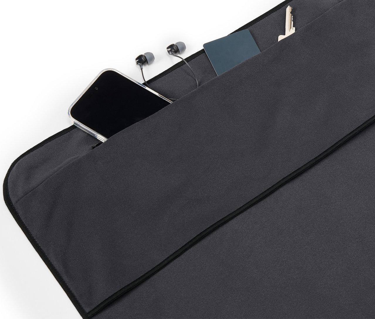 W kieszeni z czarnej tkaniny leżą telefon komórkowy, słuchawki, karta i klucz.