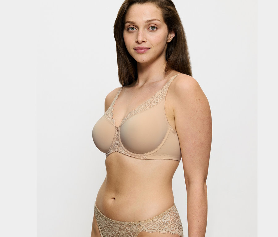 Kobieta ma na sobie biustonosz Triumph Amourette Minimizer w kolorze skóry i pasujące figi.