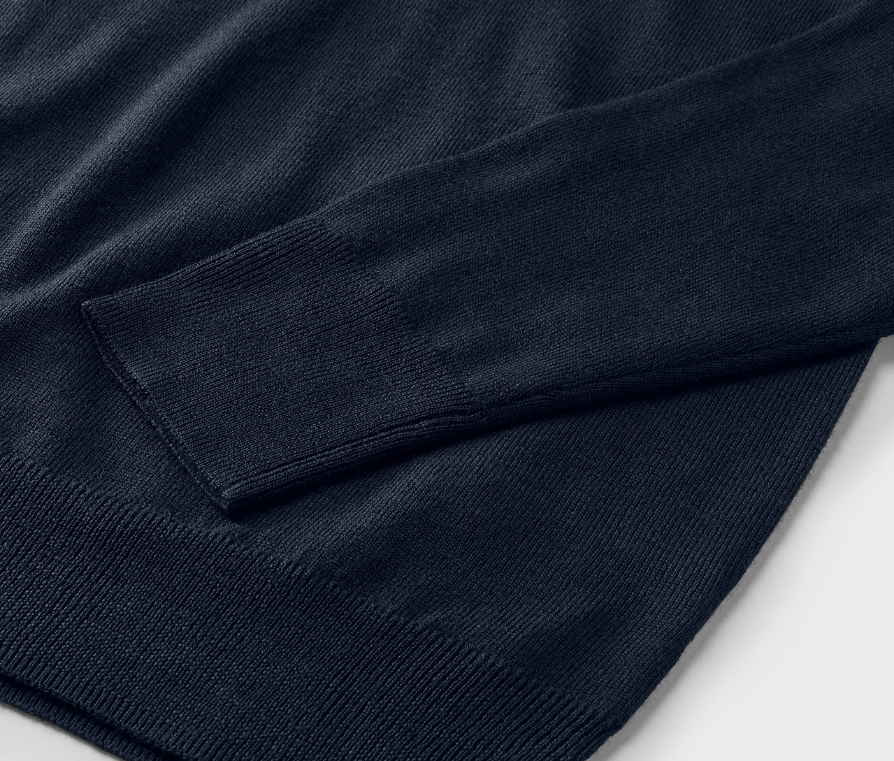 Zbliżenie na granatowy sweter z cienkiej dzianiny merino.