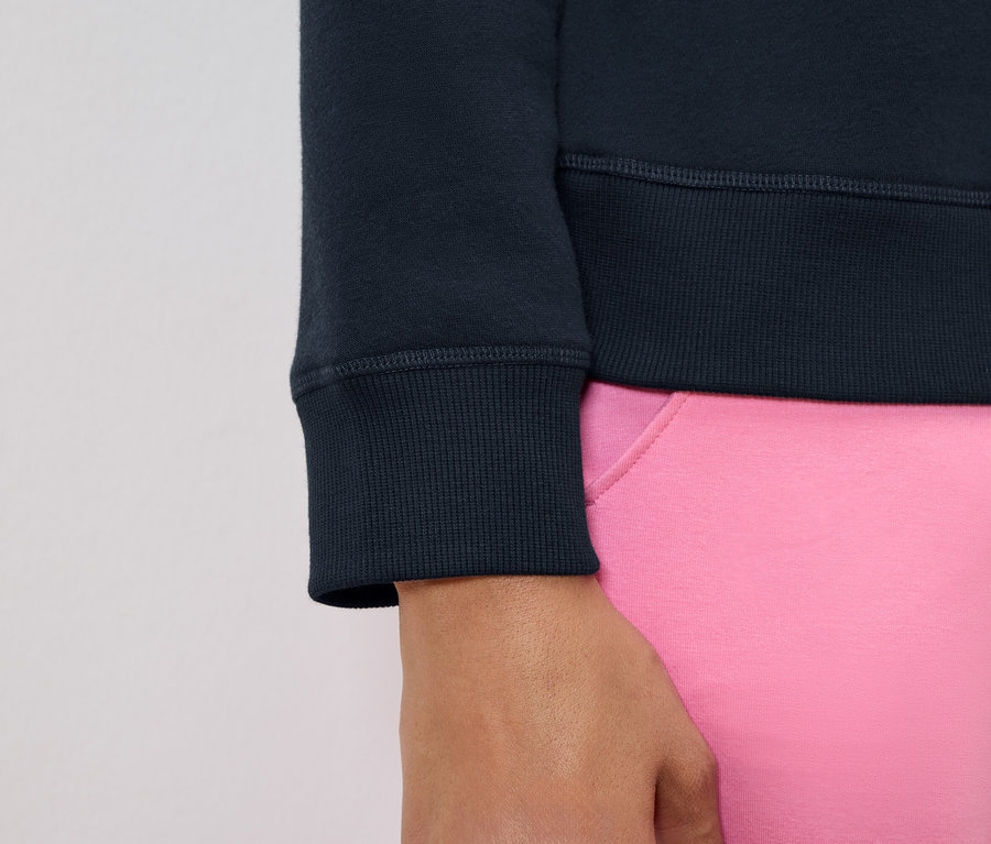 Zbliżenie na rękaw granatowej bluzy i fragment różowych spodni.