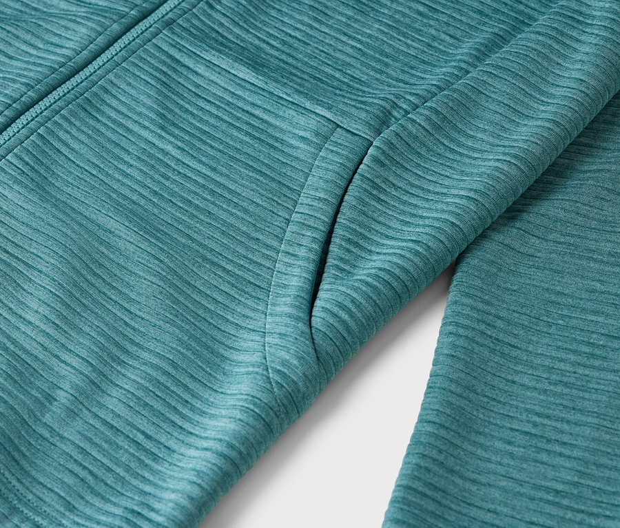 Zbliżenie turkusowej kurtki tekstylnej z zamkiem błyskawicznym i kieszenią.