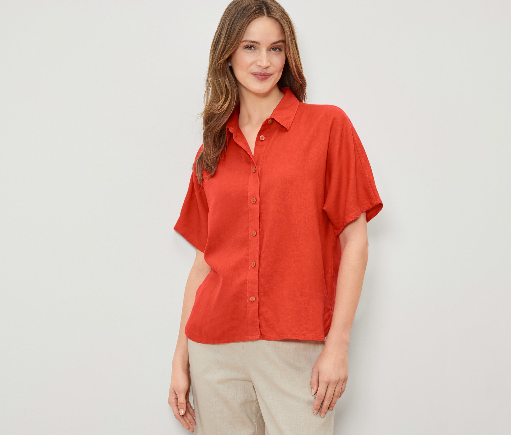 Kobieta ma na sobie pomarańczową lnianą bluzkę.