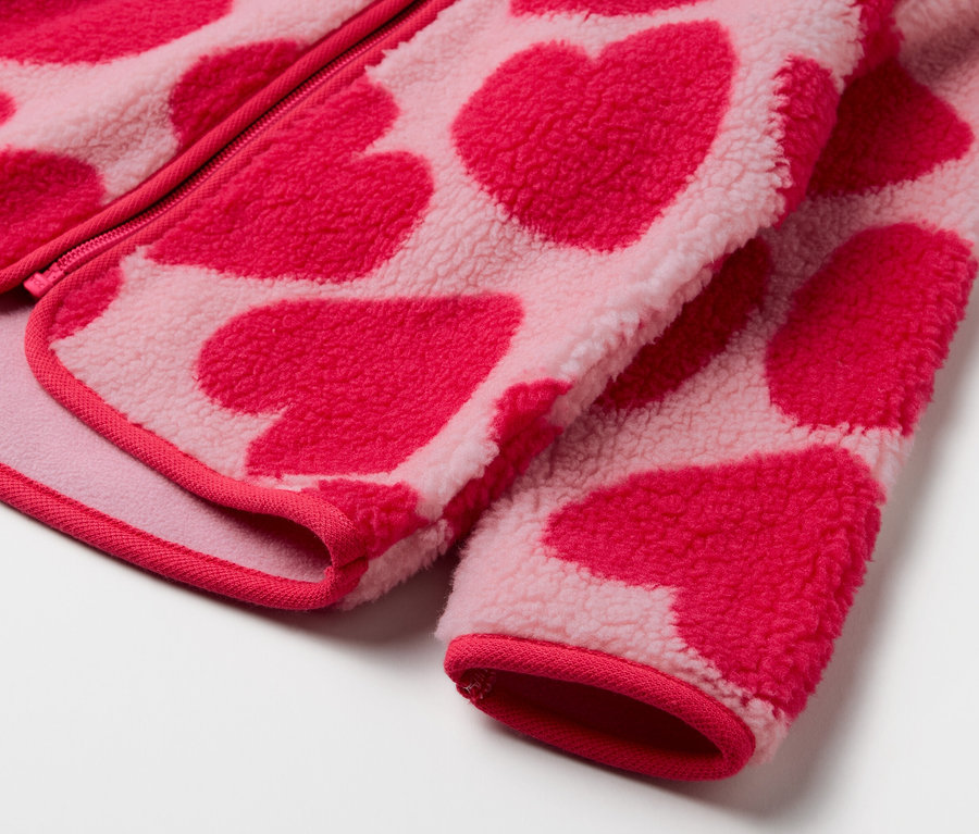 Zbliżenie na różową bluzę polarową we wzór czerwonych serc.