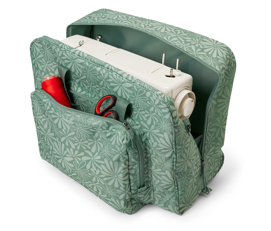 Otwarta torba na maszynę do szycia we wzór kwiatowy z maszyną do szycia, szpulą czerwonej nici i nożyczkami w środku.