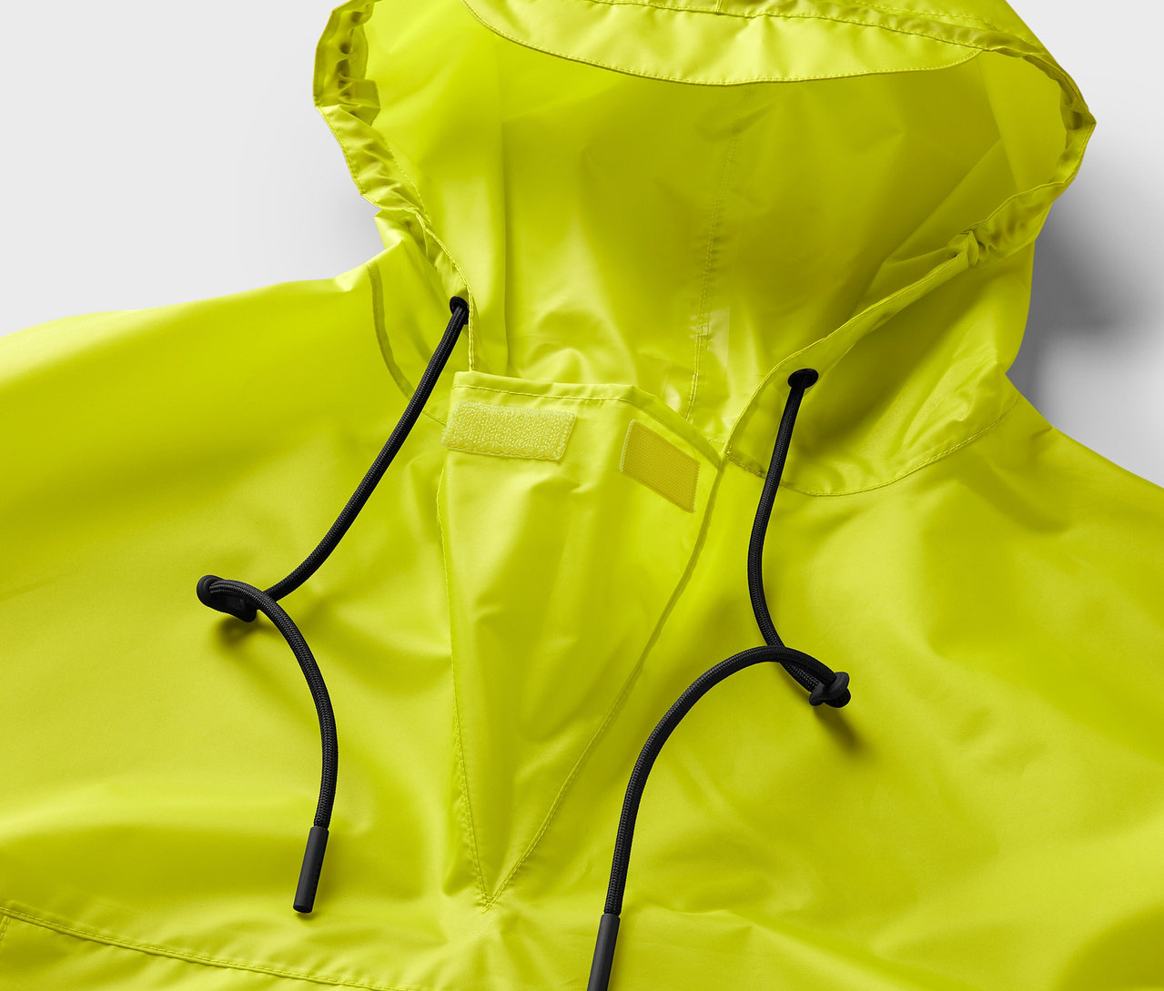 Zbliżenie na neonowożółte ponczo przeciwdeszczowe z kapturem i czarnymi sznurkami.